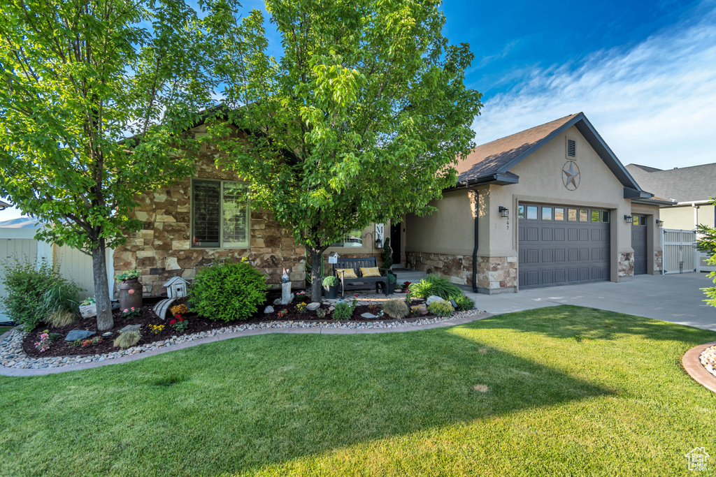 View of front of property with stone siding, a front lawn, and stucco siding