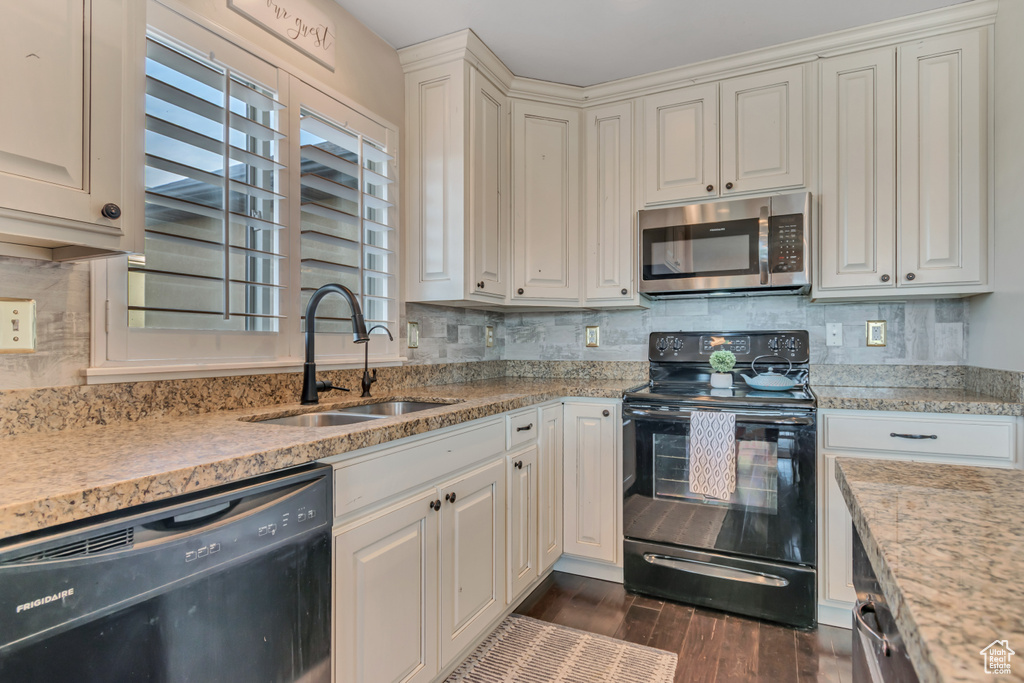 Kitchen with black appliances, a sink, dark wood-style floors, and tasteful backsplash