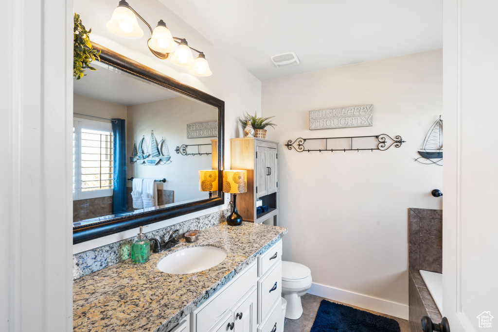 Bathroom with vanity, toilet, a tub to relax in, and baseboards