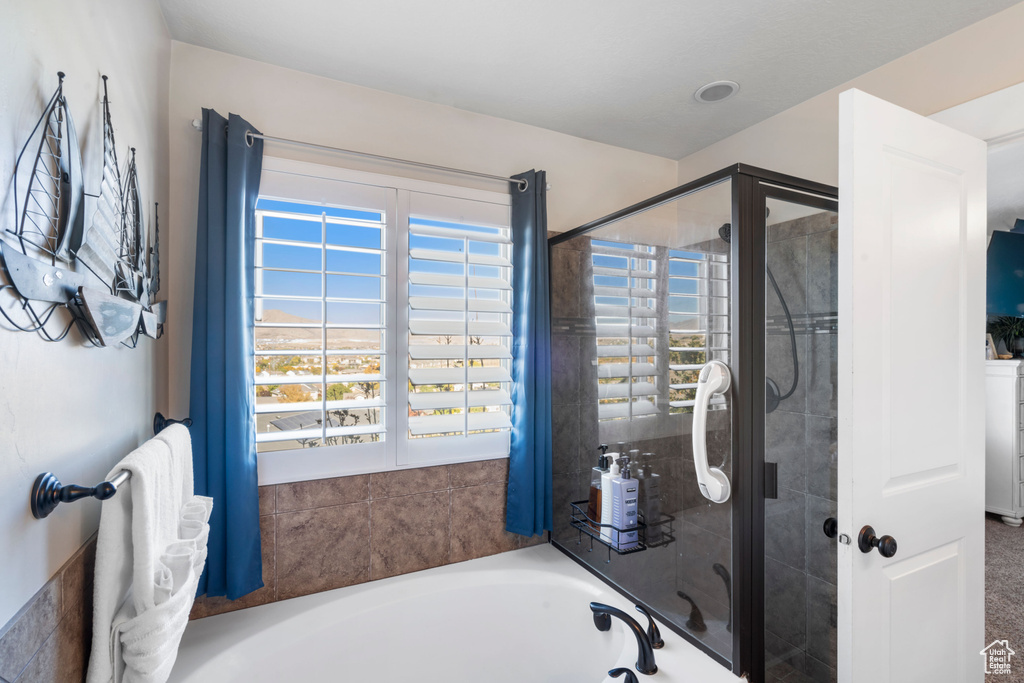 Full bath with healthy amount of natural light, a bath, and tiled shower
