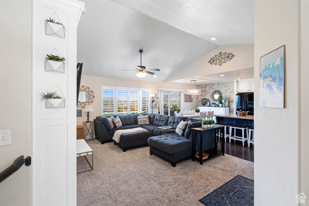 Living area with vaulted ceiling, carpet flooring, and a ceiling fan