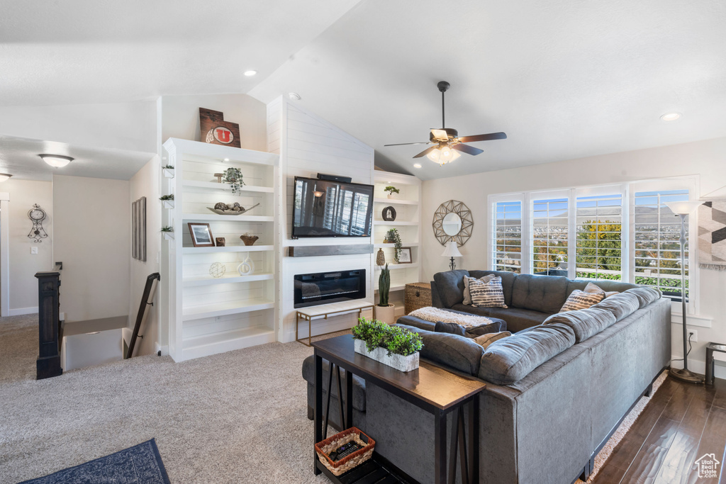 Living room featuring vaulted ceiling, ceiling fan, a glass covered fireplace, baseboards, and recessed lighting