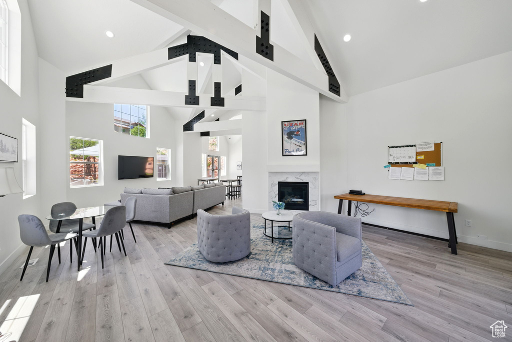 Living room with high vaulted ceiling, beamed ceiling, wood finished floors, a high end fireplace, and baseboards