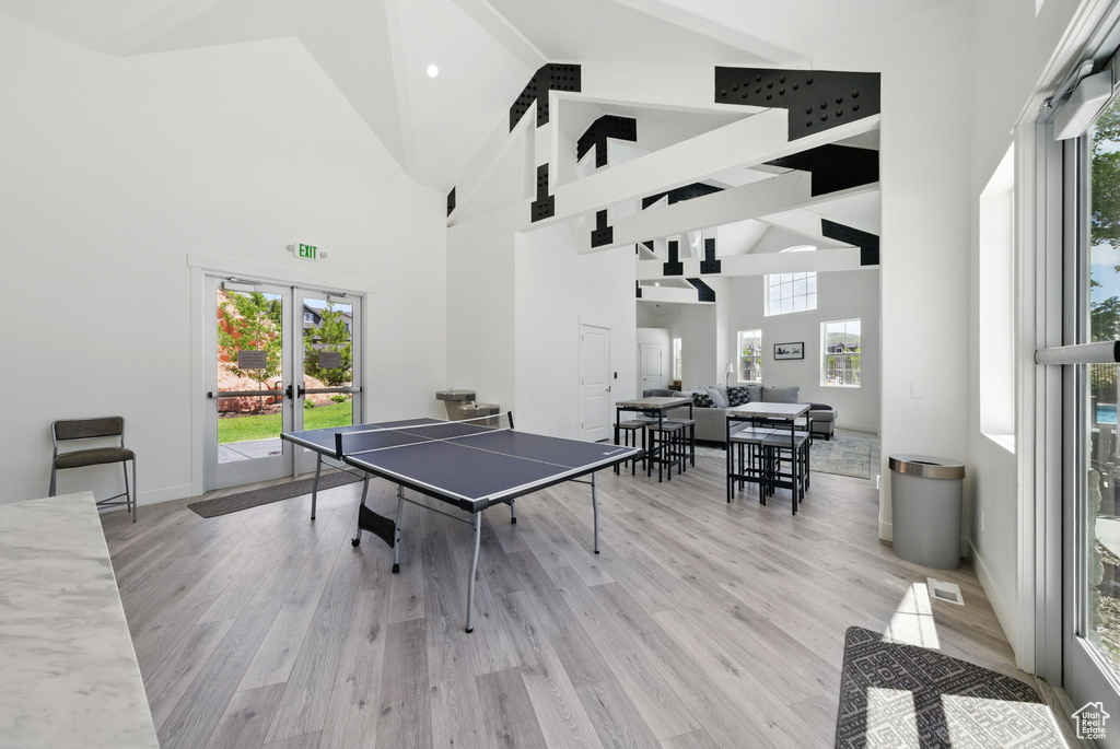 Game room with high vaulted ceiling, french doors, light wood finished floors, and baseboards