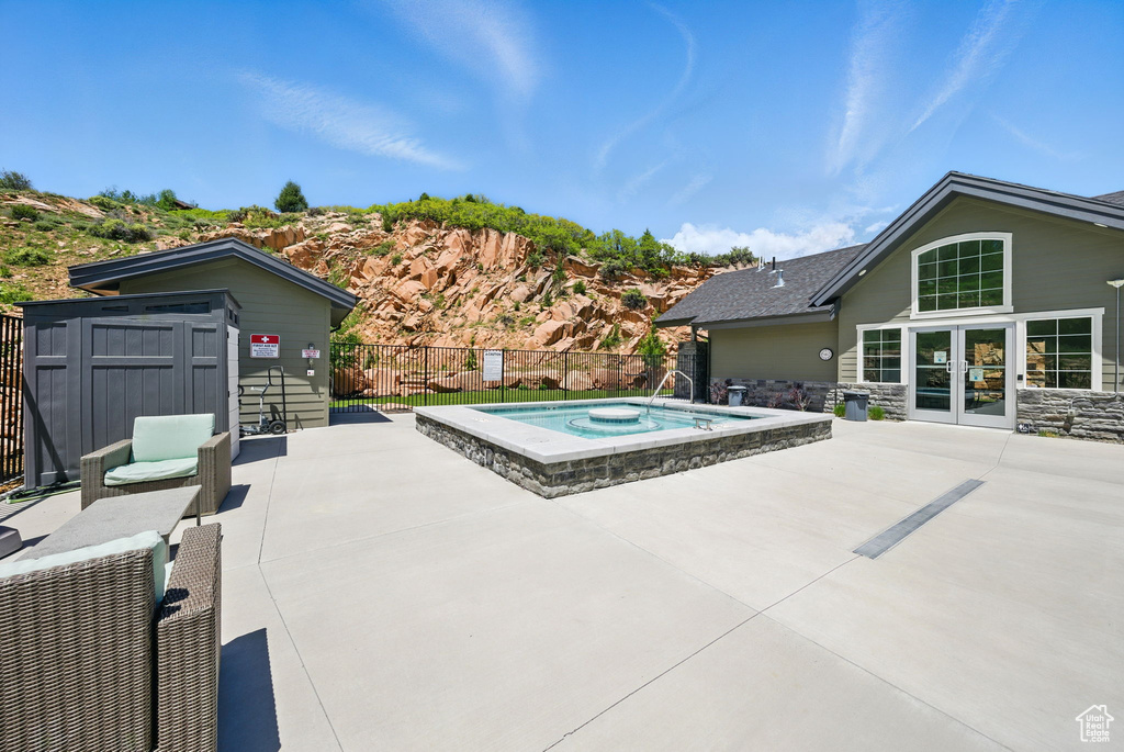 View of swimming pool featuring an outdoor hot tub, a patio area, and french doors