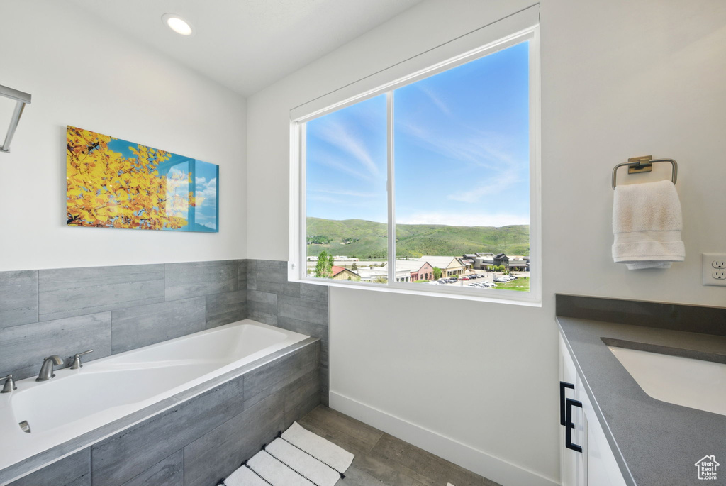 Full bathroom featuring a bath, baseboards, vanity, wood finished floors, and recessed lighting