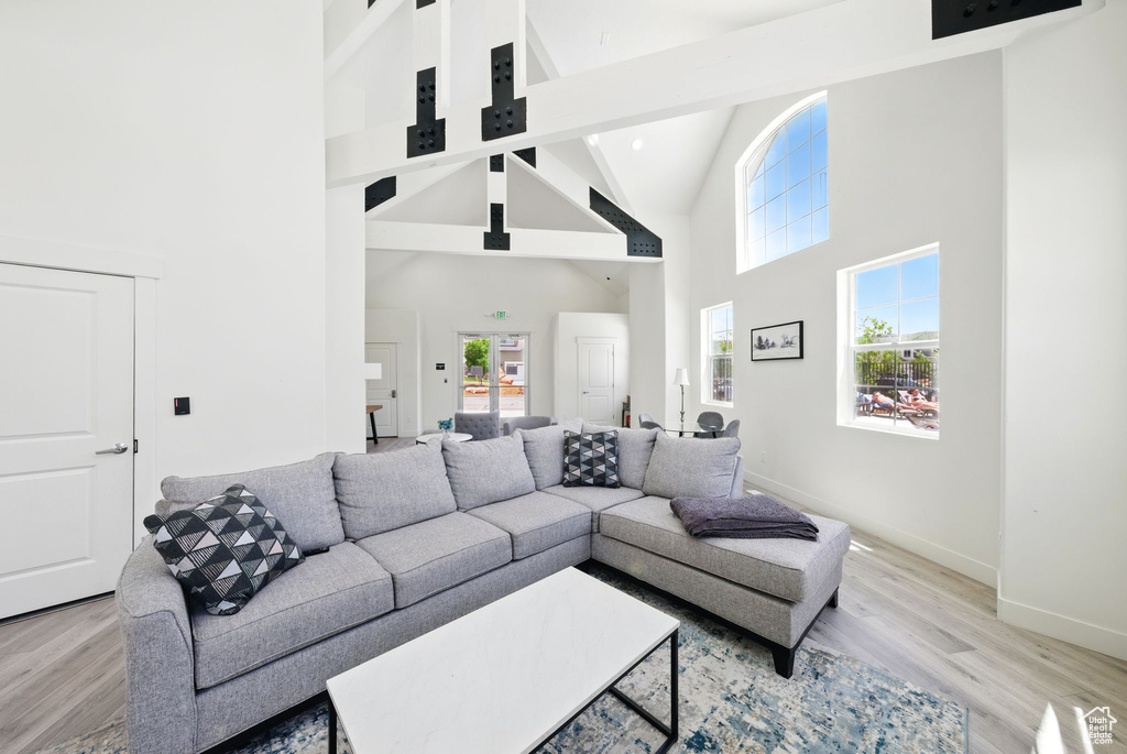 Living room with high vaulted ceiling, light wood finished floors, and baseboards