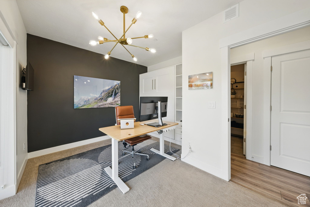 Office area with a chandelier, light colored carpet, and baseboards