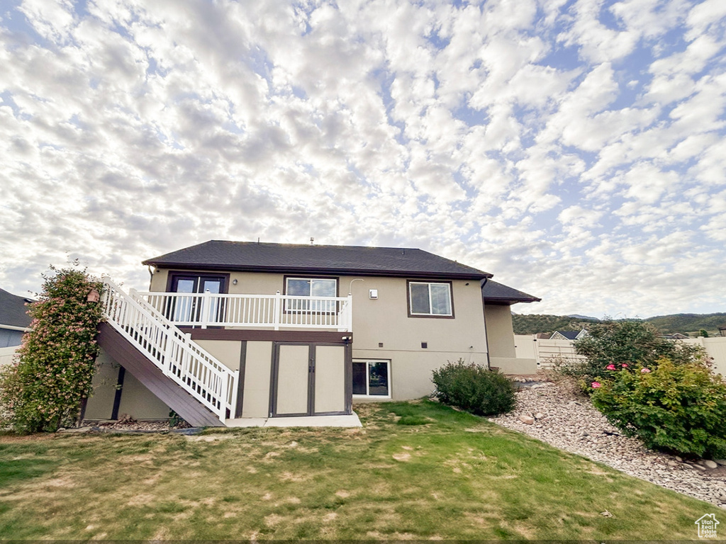 Rear view of property with stairway, stucco siding, and a wooden deck