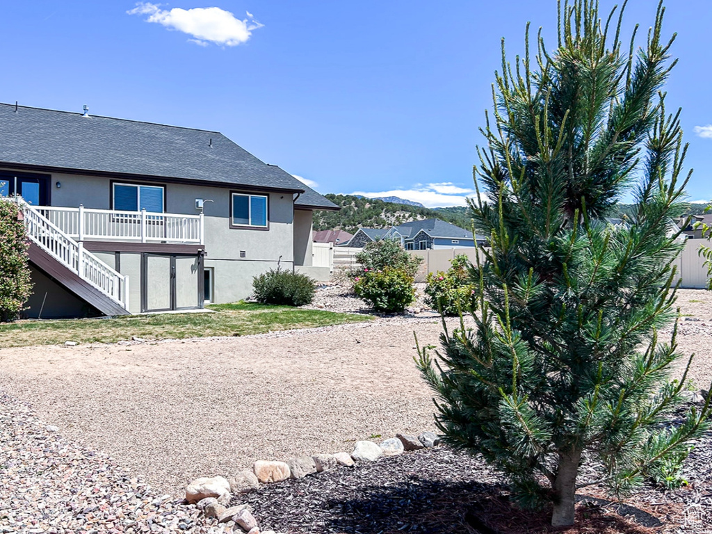 Rear view of house with stairs, a deck with mountain view, a fenced backyard, stucco siding, and a gate