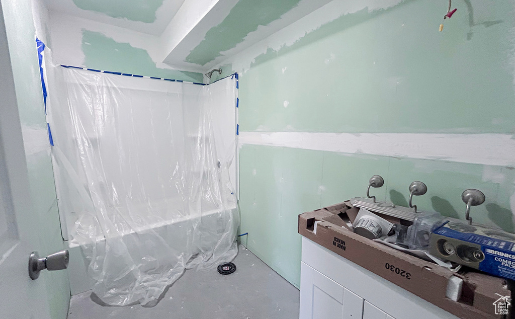 Bathroom featuring concrete flooring and shower / bath combo with shower curtain