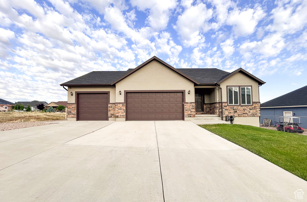 View of front of house with stucco siding, an attached garage, a front yard, and concrete driveway