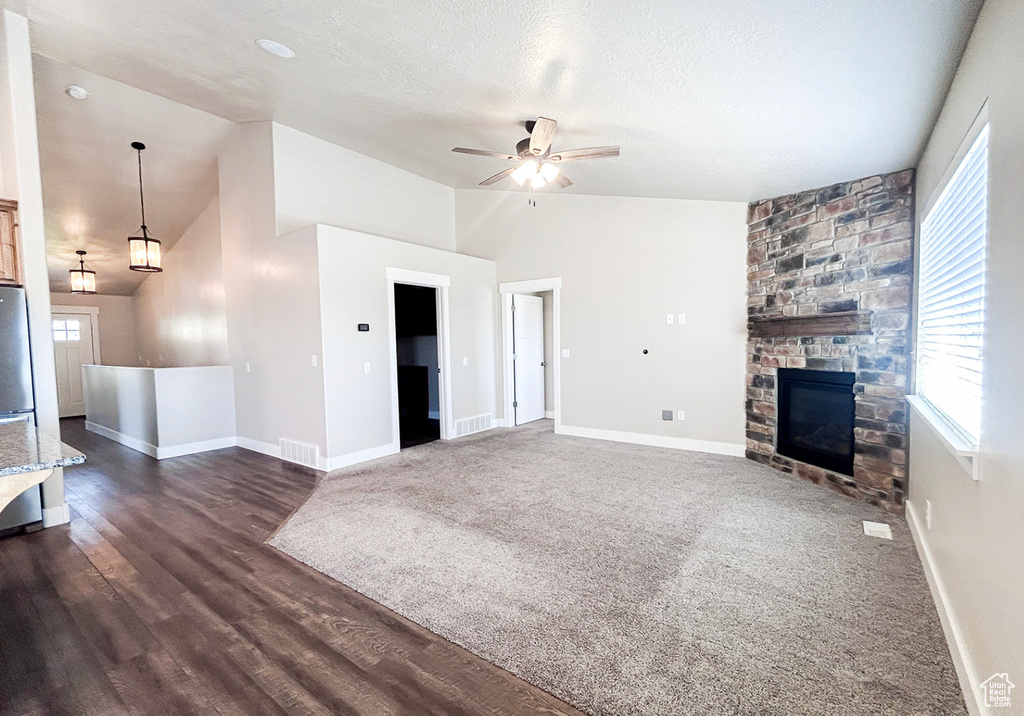 Unfurnished living room with vaulted ceiling, ceiling fan, a fireplace, and baseboards