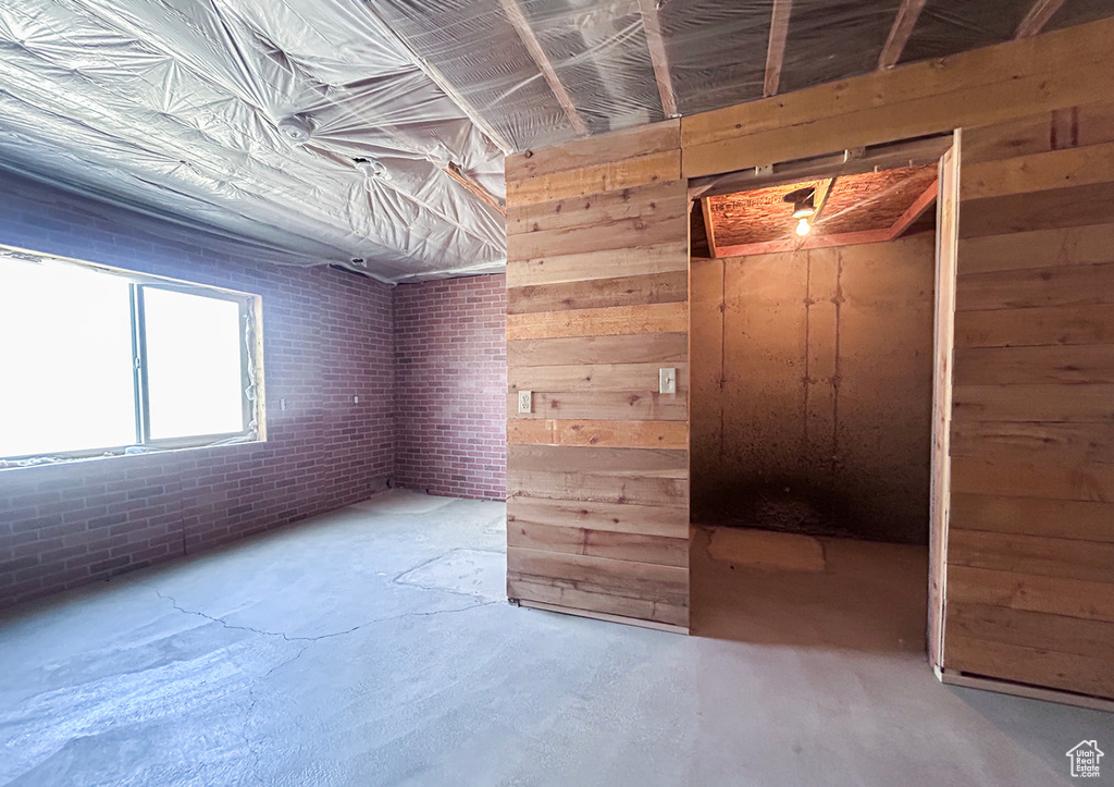 Spare room featuring unfinished concrete flooring and wooden walls