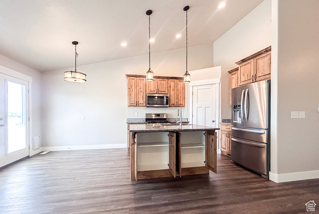 Kitchen with stainless steel appliances, baseboards, dark stone countertops, dark wood-style flooring, and a breakfast bar area