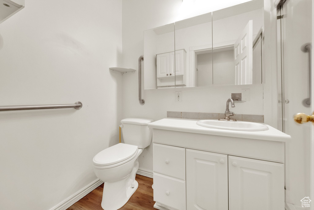 Bathroom featuring vanity, toilet, wood finished floors, and baseboards