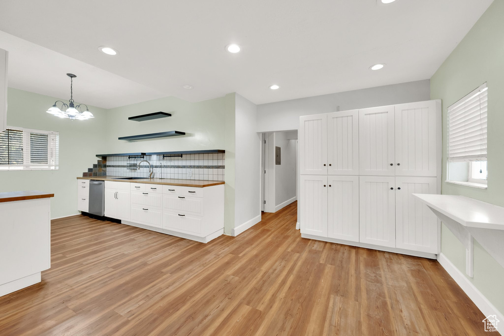 Kitchen featuring stainless steel dishwasher, a sink, light wood finished floors, white cabinets, and recessed lighting