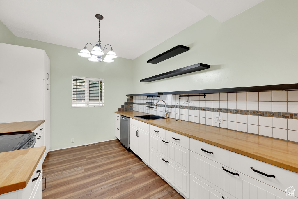 Kitchen featuring butcher block counters, a sink, stainless steel dishwasher, open shelves, and backsplash