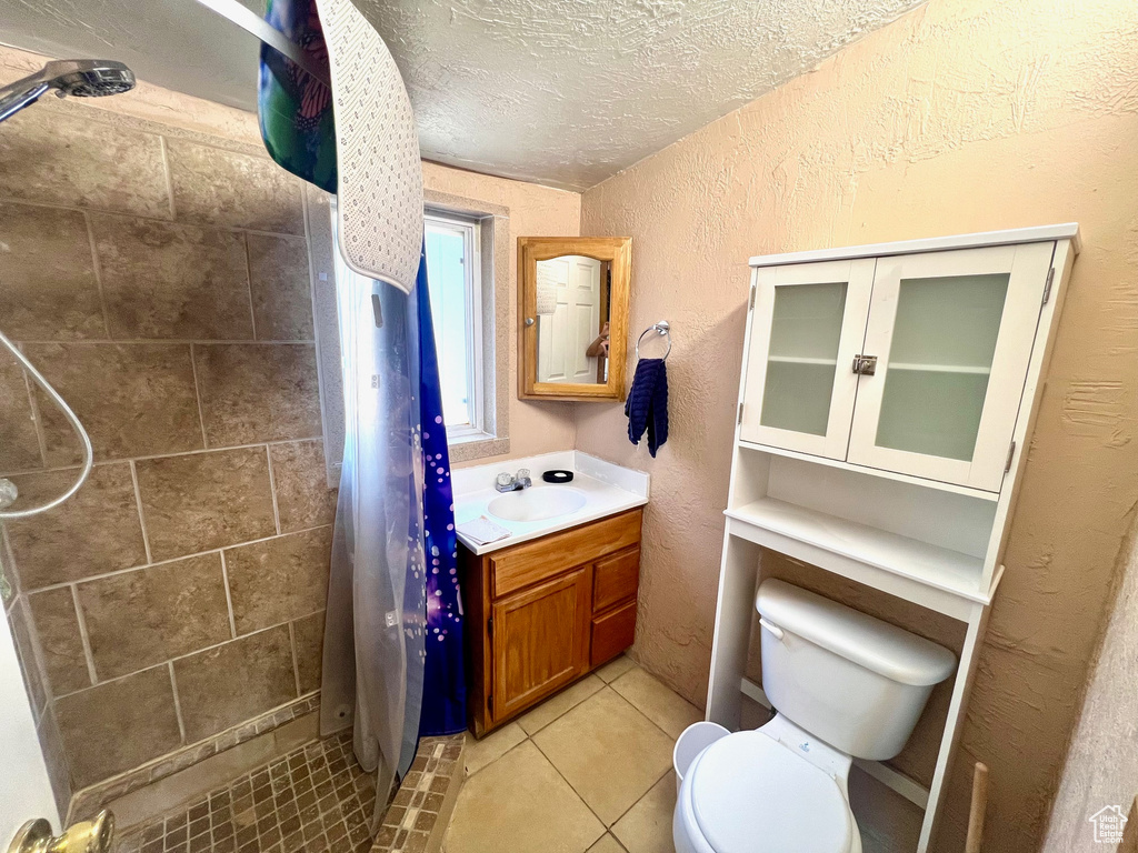 Full bath featuring a stall shower, toilet, a textured wall, a textured ceiling, and vanity