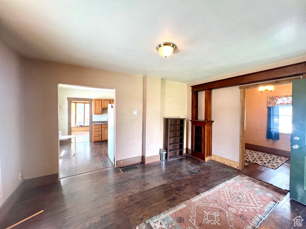 Unfurnished living room with dark wood-type flooring, baseboards, and a textured ceiling