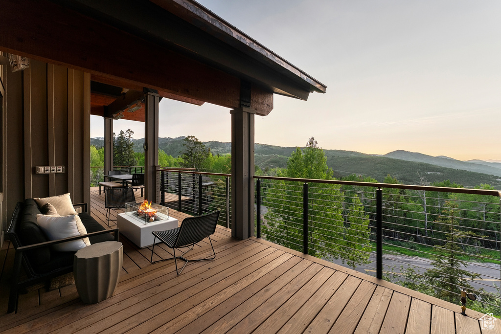 Wooden deck featuring an outdoor fire pit and a mountain view