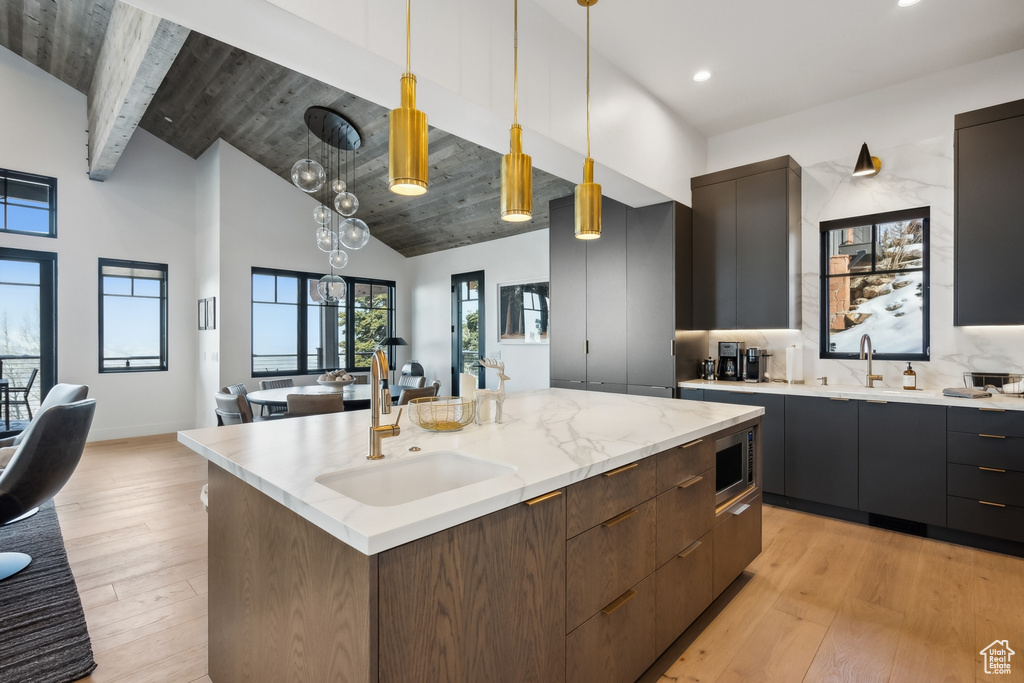 Kitchen with a sink, modern cabinets, hanging light fixtures, recessed lighting, and stainless steel microwave