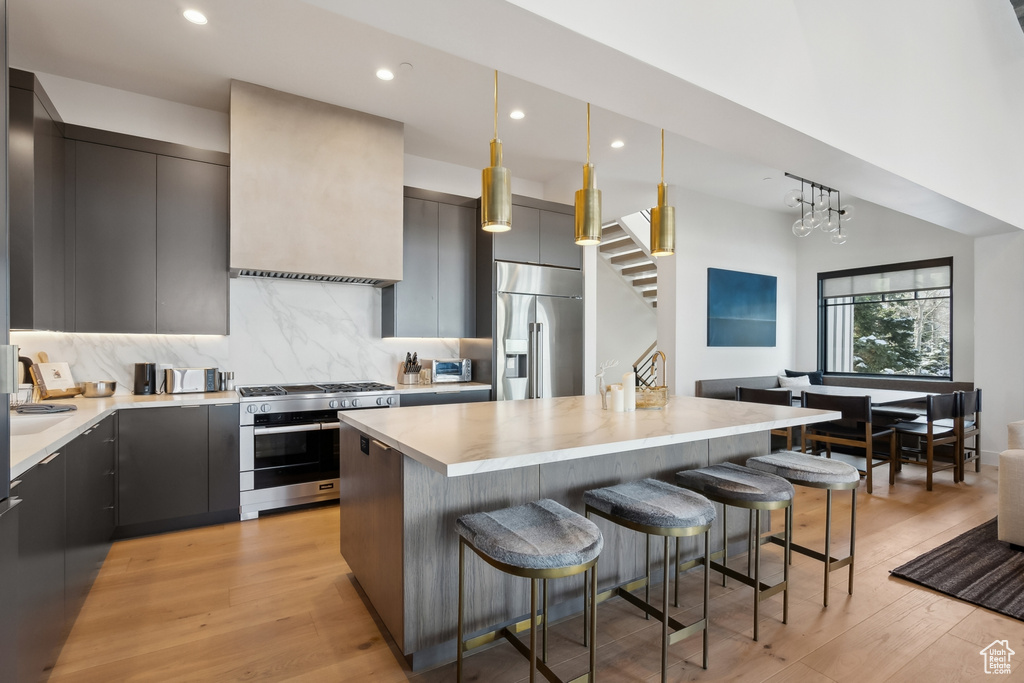 Kitchen featuring appliances with stainless steel finishes, a kitchen bar, modern cabinets, light countertops, and recessed lighting