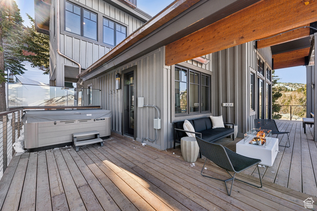Deck with a hot tub and an outdoor living space with a fire pit