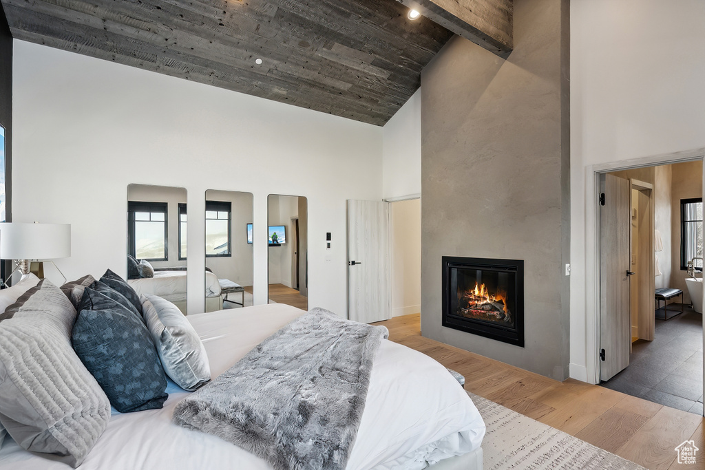 Bedroom with high vaulted ceiling, wood finished floors, a fireplace, and arched walkways
