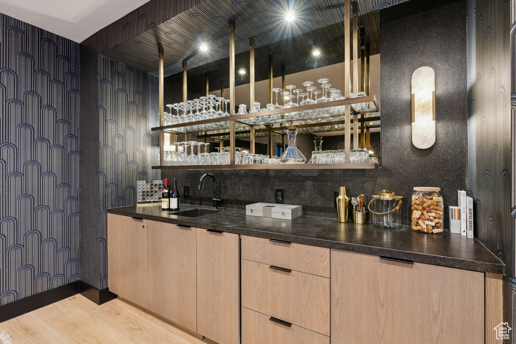 Indoor wet bar featuring wood finished floors and backsplash