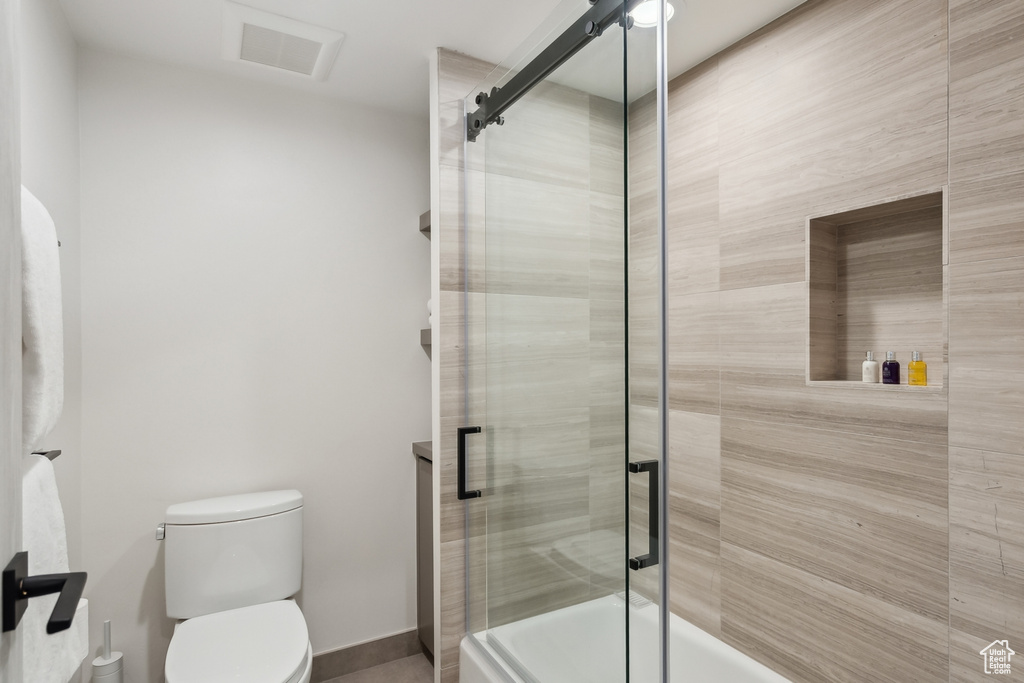 Full bath featuring enclosed tub / shower combo, toilet, and a sauna