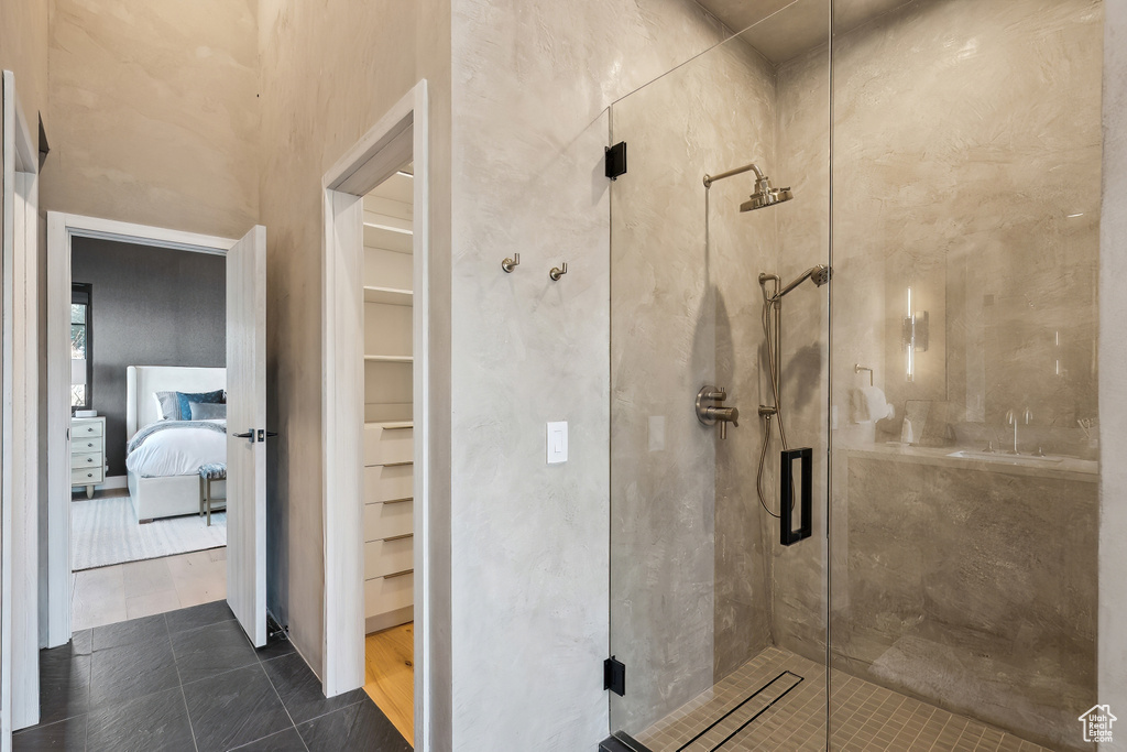 Ensuite bathroom featuring a shower stall, a walk in closet, and tile patterned flooring