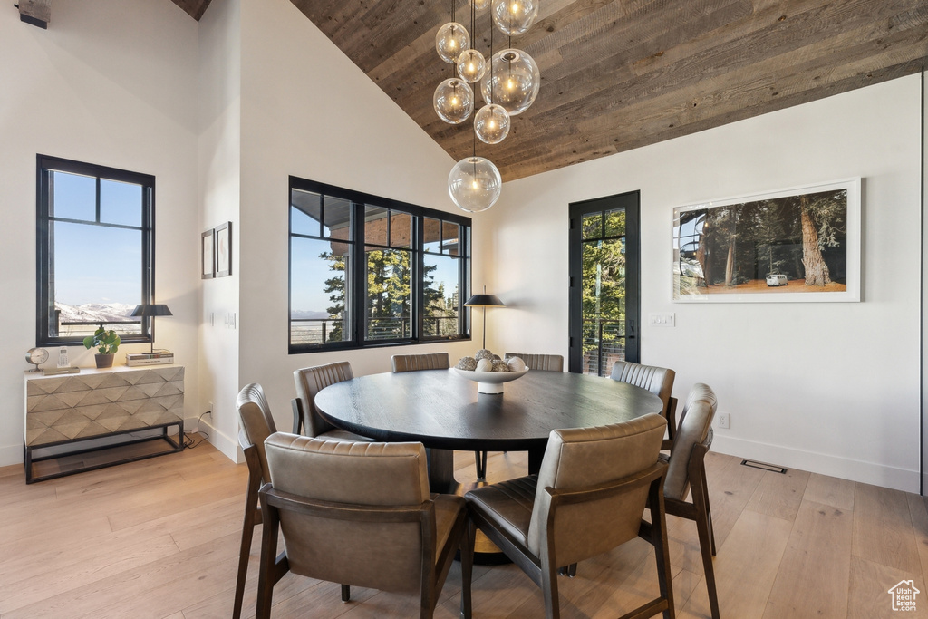 Dining area with wooden ceiling, light wood-style flooring, baseboards, a chandelier, and high vaulted ceiling