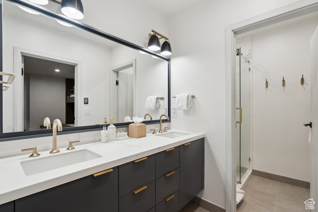 Full bathroom with double vanity, a stall shower, baseboards, and tile patterned flooring