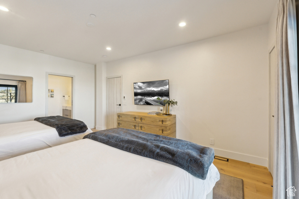 Bedroom with light wood finished floors, recessed lighting, baseboards, and connected bathroom