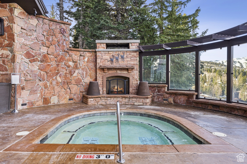 View of pool with an outdoor stone fireplace, an in-ground hot tub, and a pool