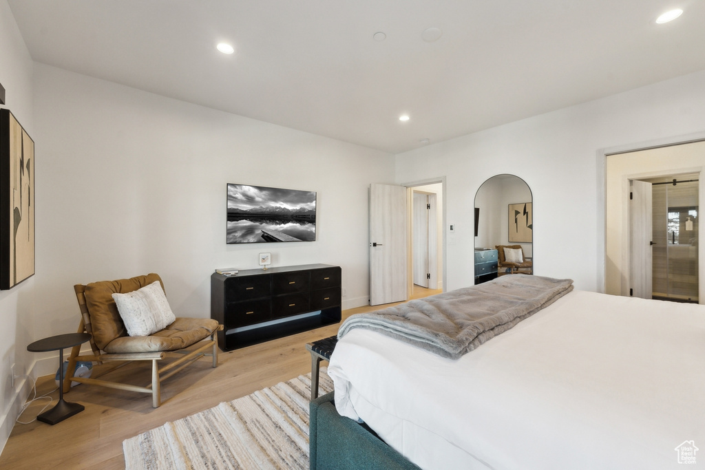 Bedroom featuring arched walkways, light wood-style floors, recessed lighting, and baseboards