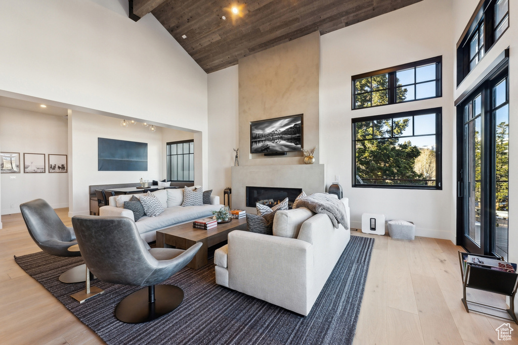 Living area featuring high vaulted ceiling, wood finished floors, a large fireplace, recessed lighting, and baseboards