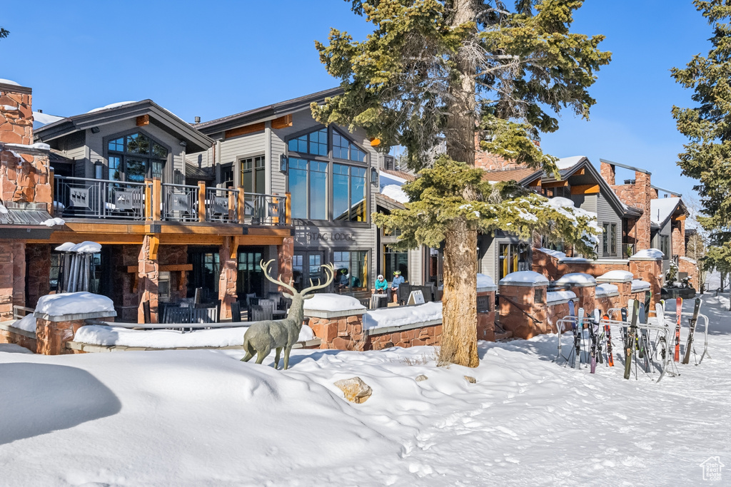 Snow covered back of property with a wooden deck