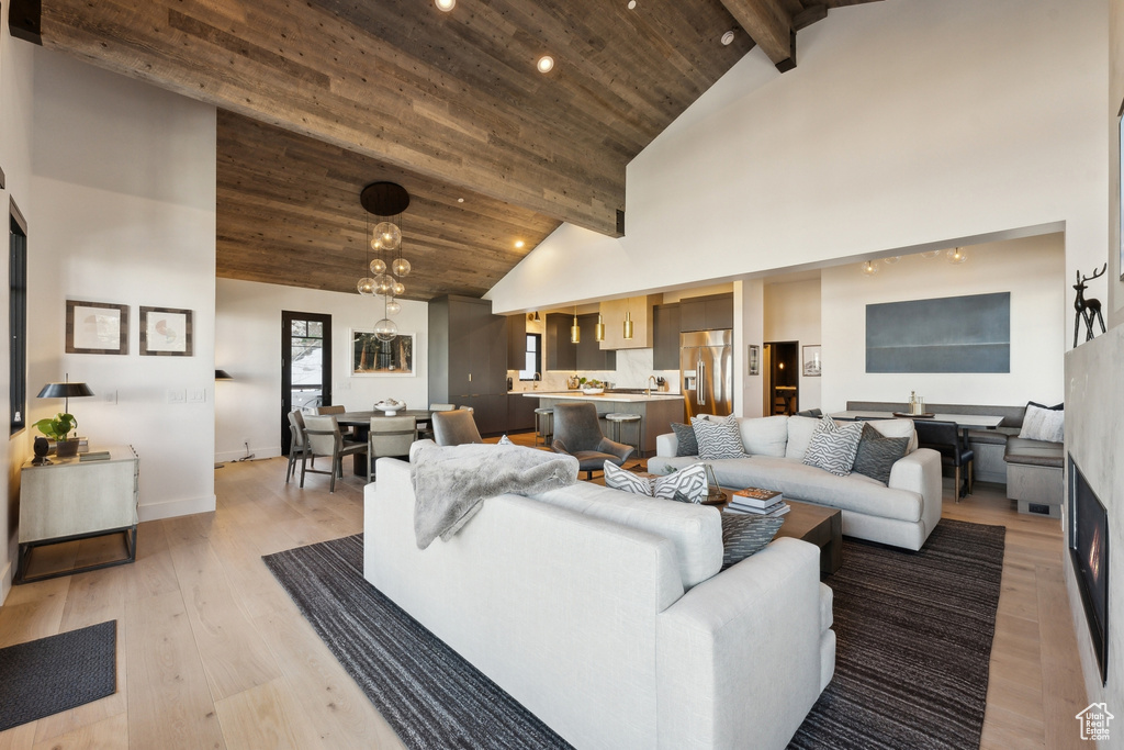 Living area featuring high vaulted ceiling, light wood-type flooring, recessed lighting, wood ceiling with exposed beams, and baseboards