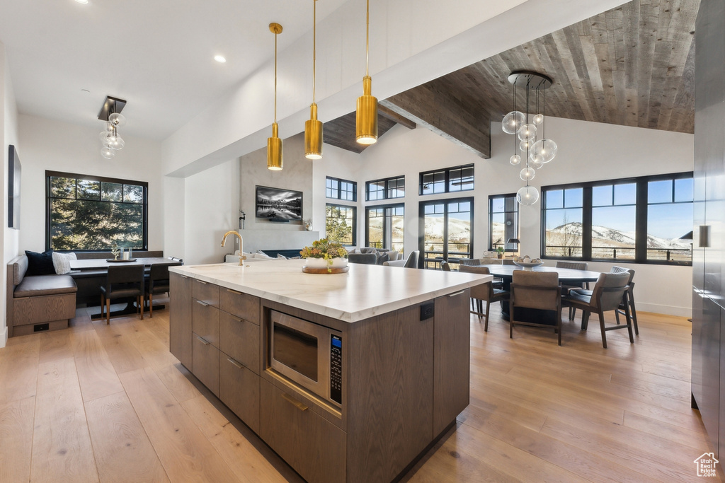 Kitchen featuring open floor plan, modern cabinets, stainless steel microwave, light wood-style flooring, and recessed lighting
