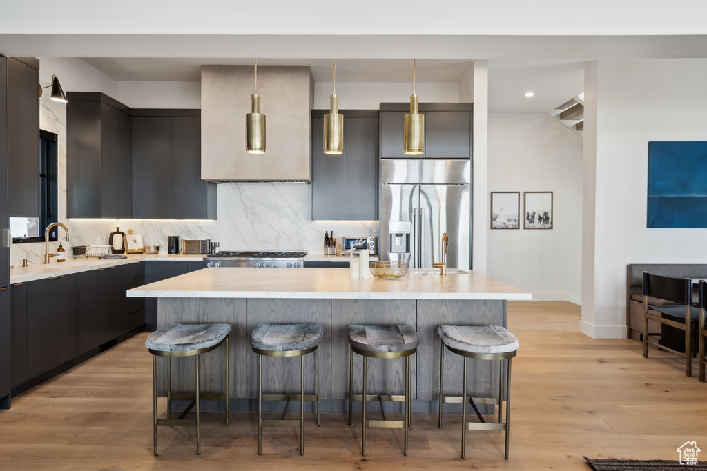 Kitchen featuring stainless steel fridge, a kitchen breakfast bar, light countertops, pendant lighting, and recessed lighting