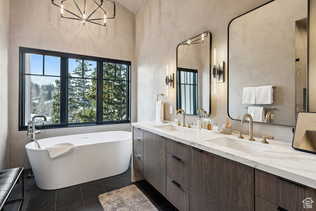 Bathroom with double vanity, a soaking tub, and a chandelier
