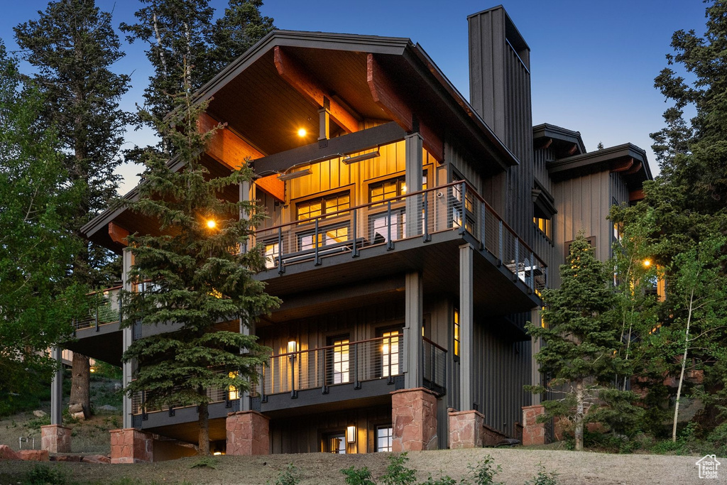 Rear view of house featuring a balcony, board and batten siding, and a chimney