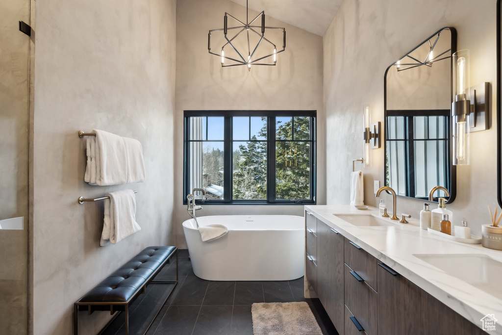 Full bathroom featuring a freestanding tub, double vanity, high vaulted ceiling, and a chandelier
