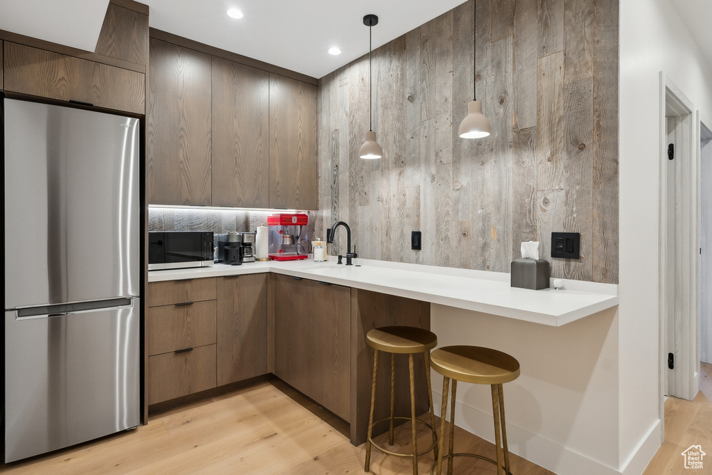 Kitchen with freestanding refrigerator, modern cabinets, light wood finished floors, light countertops, and recessed lighting