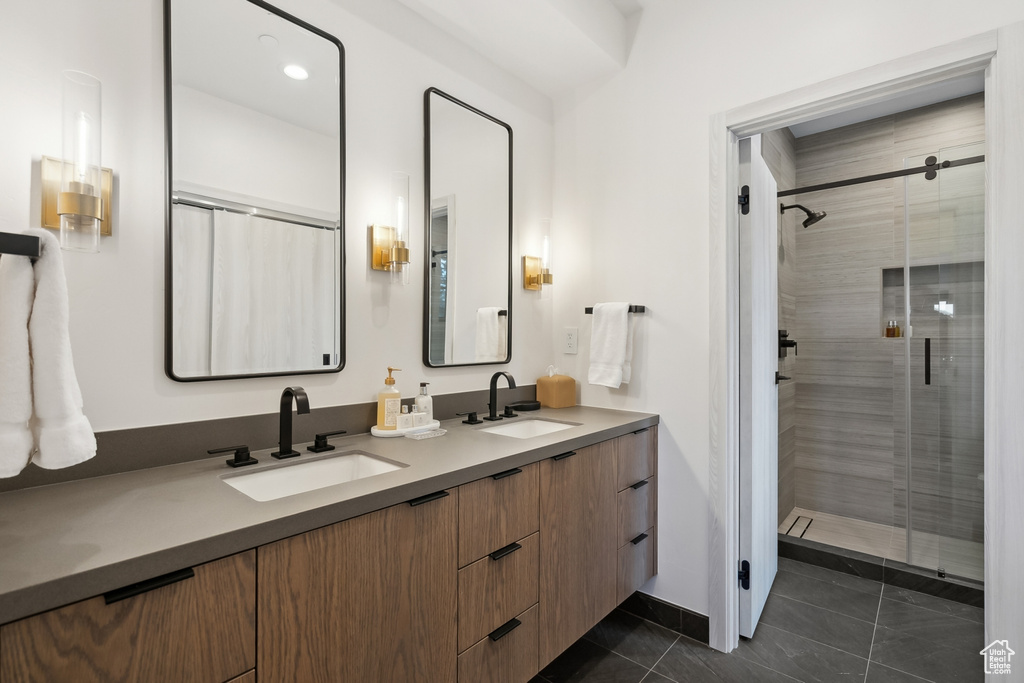 Full bathroom featuring a shower stall, double vanity, and tile patterned floors