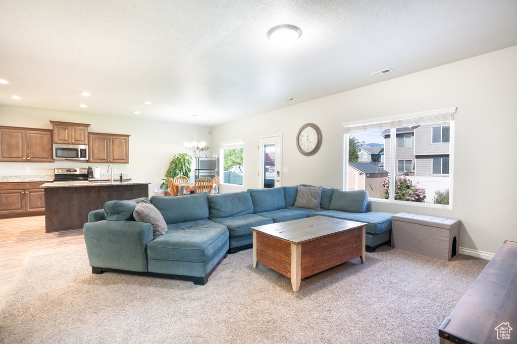 Living room with a chandelier, recessed lighting, and light carpet