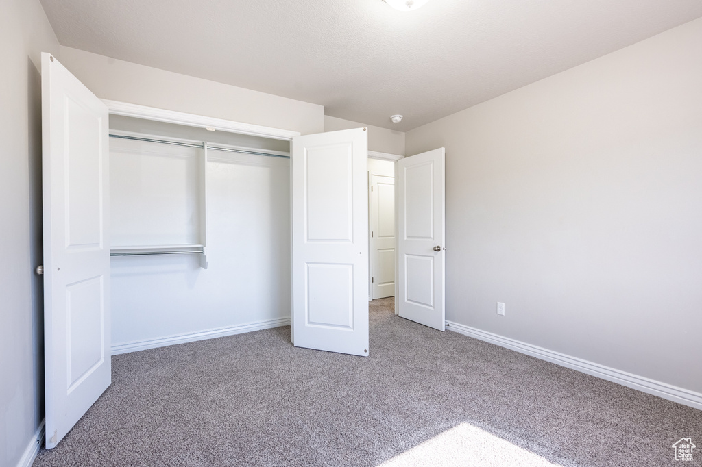Unfurnished bedroom featuring carpet floors, baseboards, and a closet