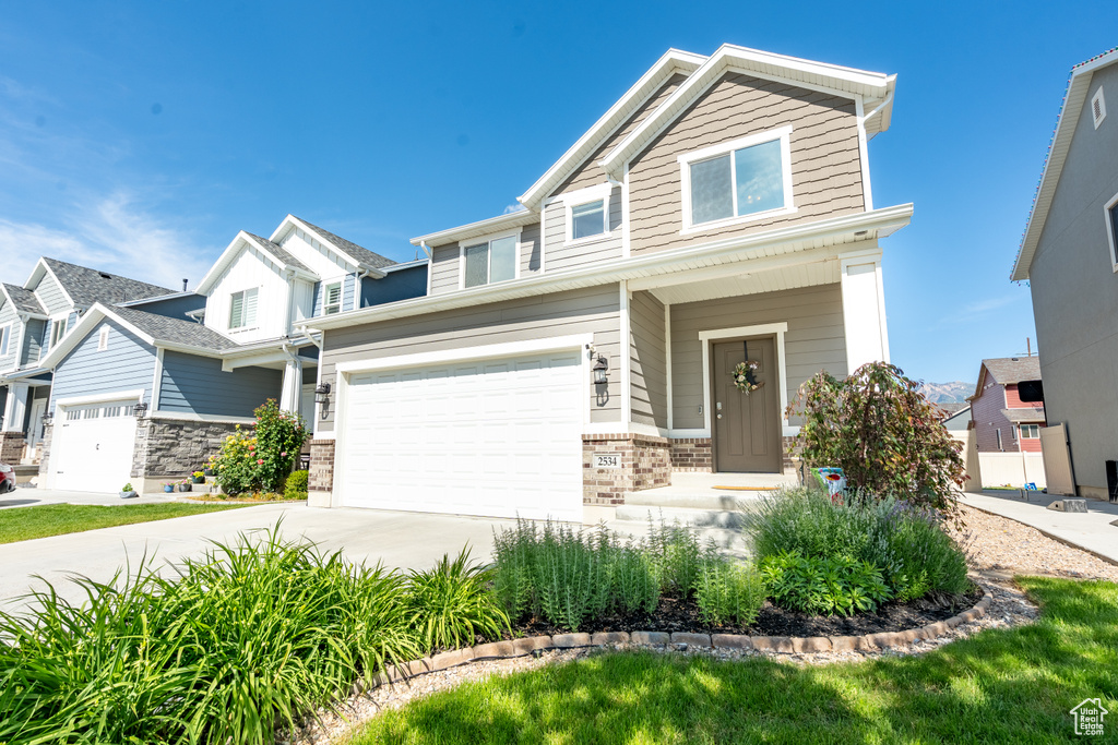 View of front facade featuring driveway, an attached garage, and brick siding